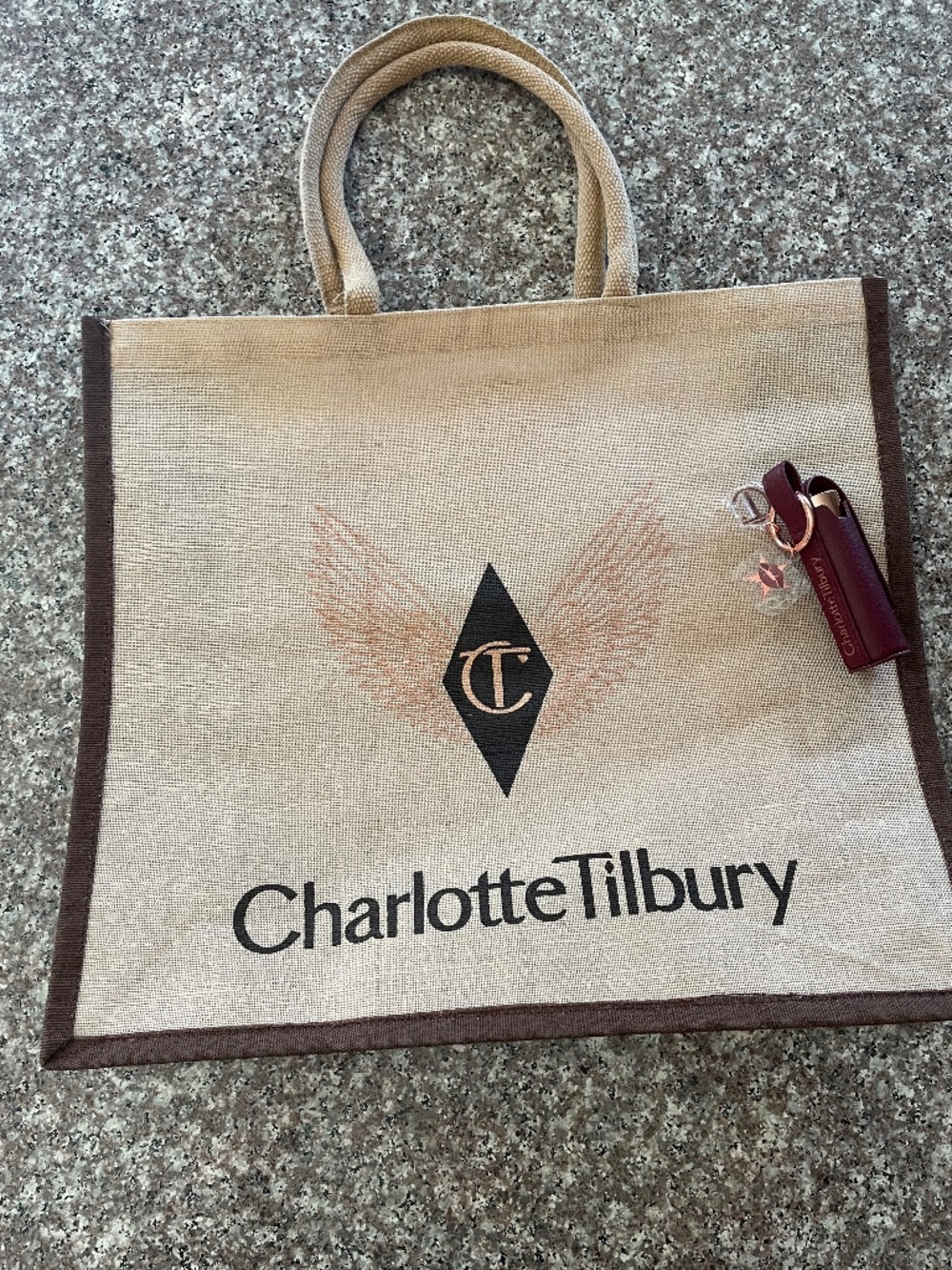 Charlotte Tilbury Airbrush Flawless Setting Spray, a keychain charm, and a tote